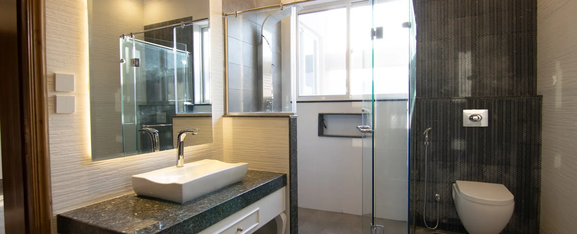 A renovated bathroom with tiled walls, a glass shower screen and modern fittings