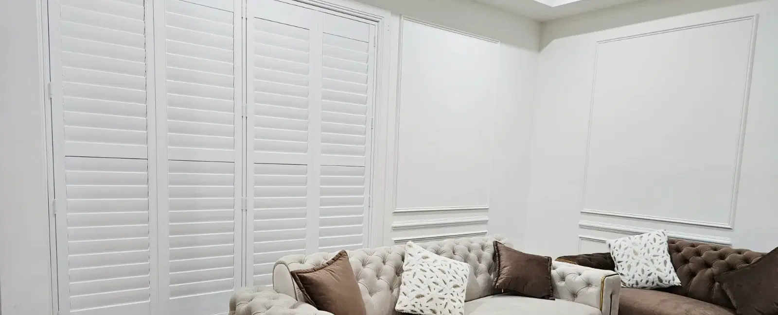 A living room window fitted with plantation shutters